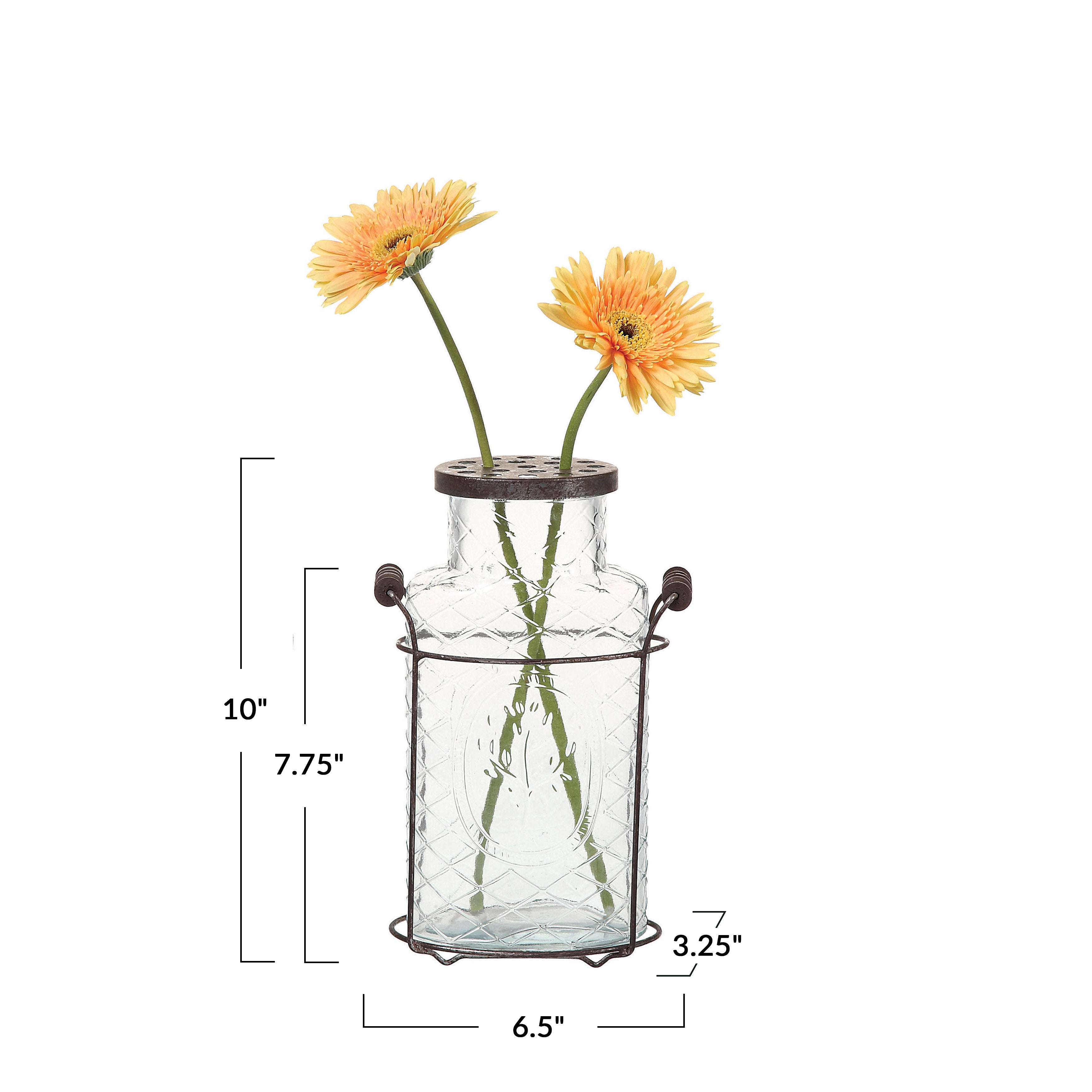 A clear glass vase with a metal stand and frog lid, containing two orange flowers.
